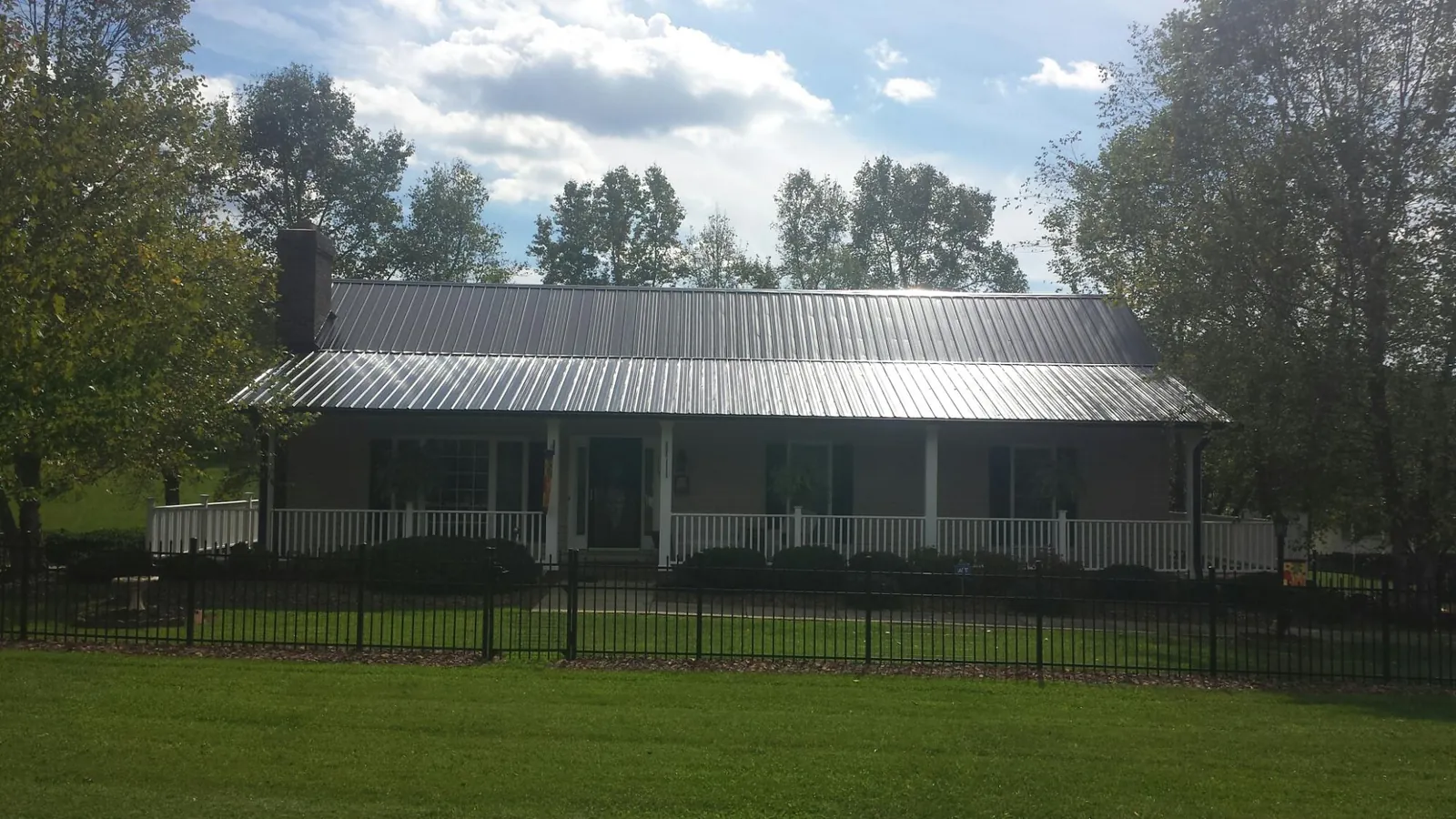 Gray metal roof on a brick ranch with a full width front porch — Gutter Guard Installation work by our crew in Dalton
